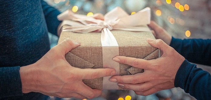 a couple both holding and exchanging  a beautifully wrapped gift