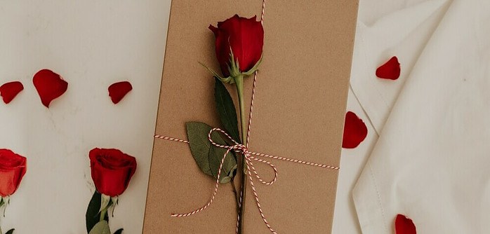 a gift wrapped beautifully with a single rose on top for valentine's day